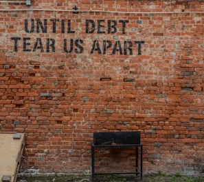 Until debt tear us apart printed red brick wall at daytime