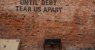 Until debt tear us apart printed red brick wall at daytime