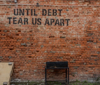 Until debt tear us apart printed red brick wall at daytime