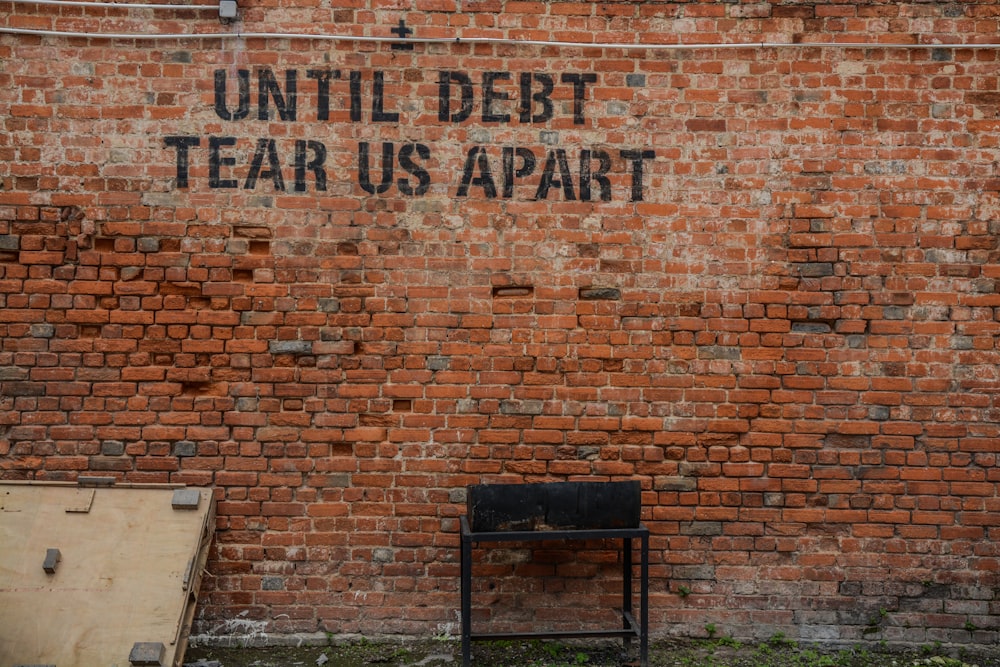 Until debt tear us apart printed red brick wall at daytime