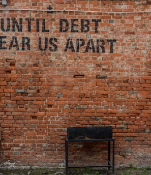 Until debt tear us apart printed red brick wall at daytime