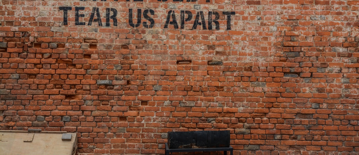 Until debt tear us apart printed red brick wall at daytime