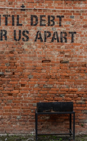 Until debt tear us apart printed red brick wall at daytime