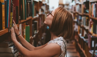 woman standing between library book shelves