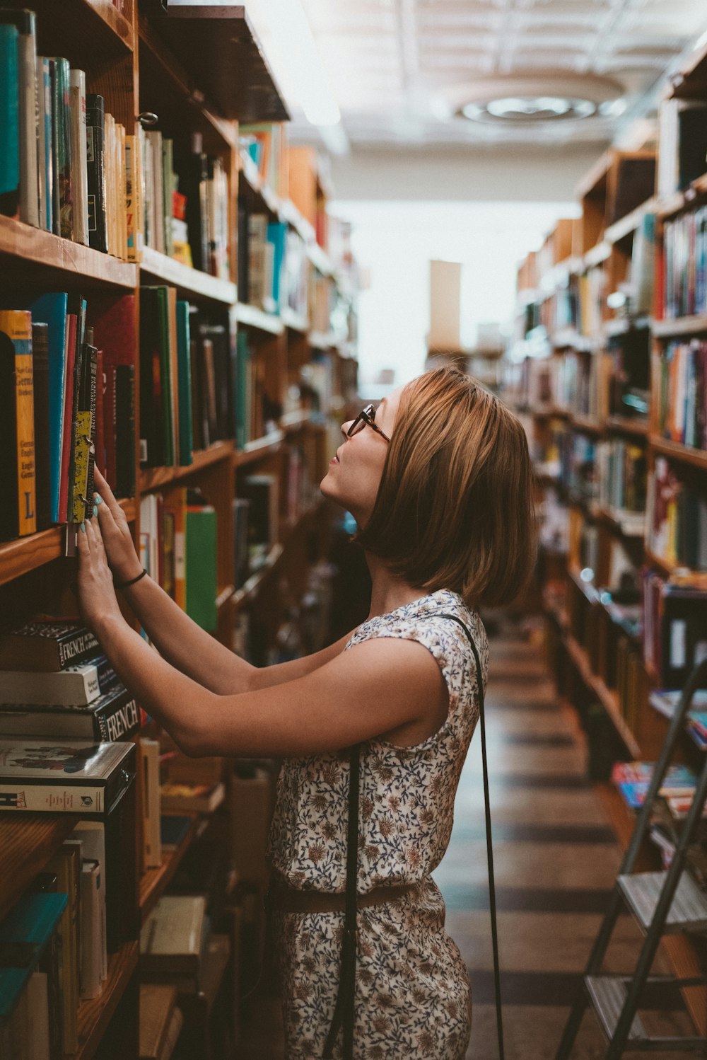 woman standing between library book shelves