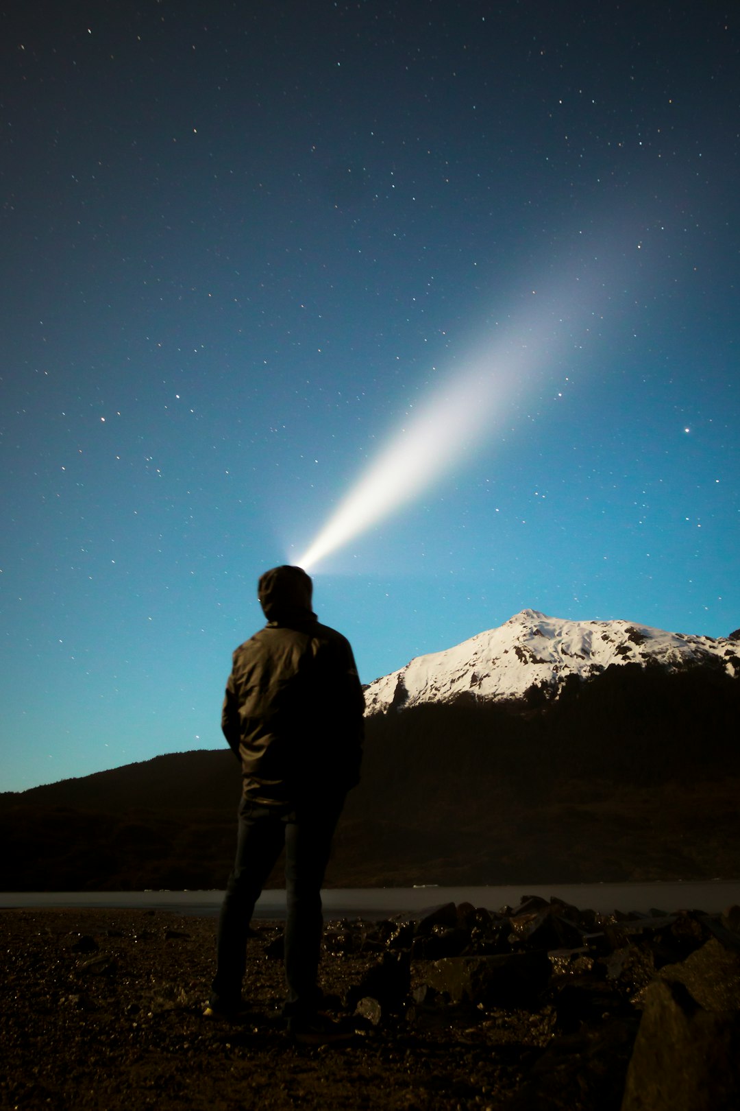 man standing in front of mountain watching light on sky