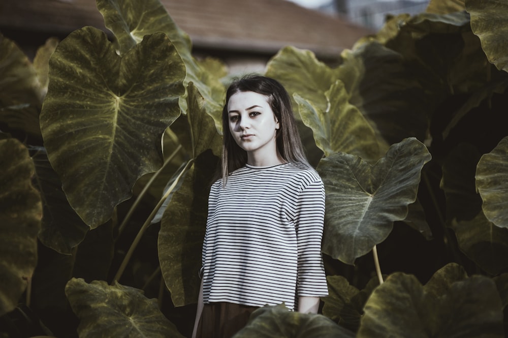 Ragazza che indossa una camicia a maniche lunghe in bianco e nero circondata da piante verdi