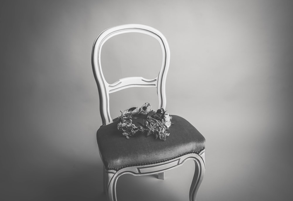 Photographie en niveaux de gris diadème de fleurs sur chaise sans accoudoirs
