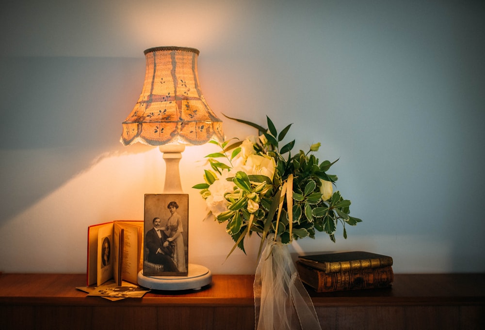 a table with a lamp and a vase with flowers on it