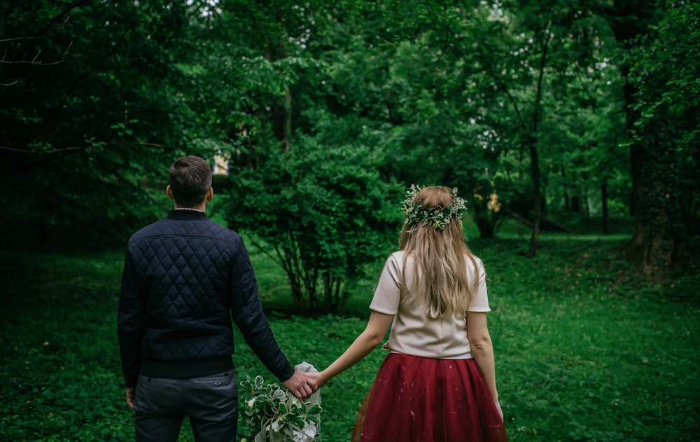 woman and man standing holding hands facing trees