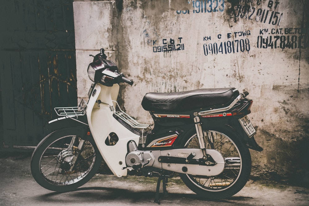 Moto blanche et noire garée près du mur