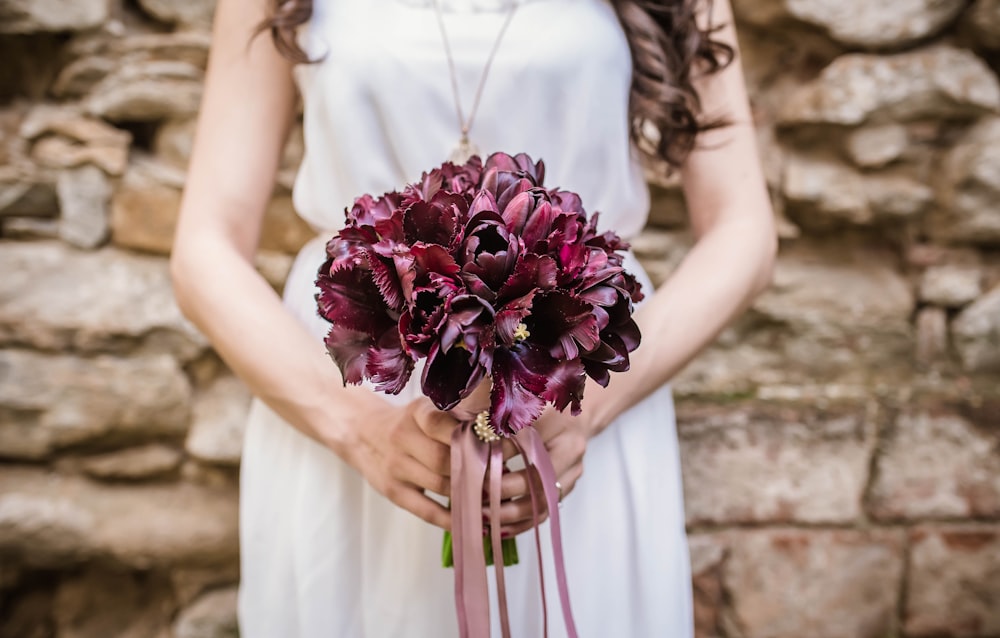 mujer sosteniendo ramo de flores púrpuras