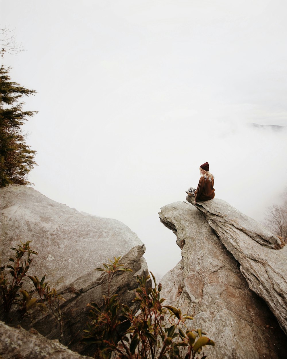 Frau sitzt auf braunem Felsen