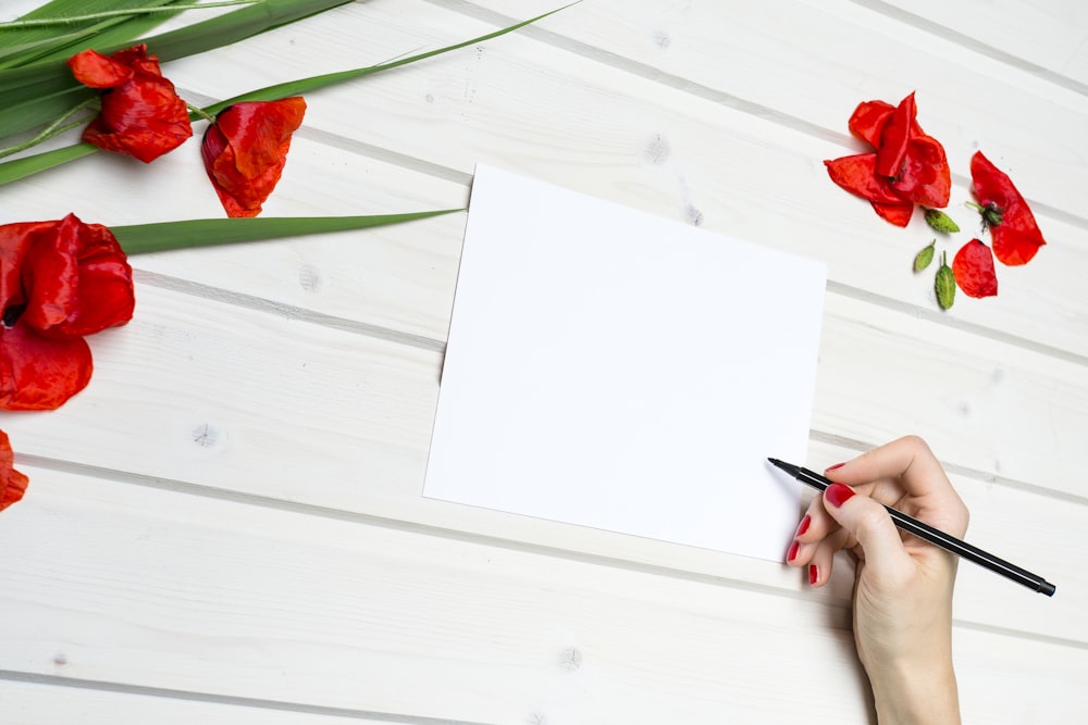 woman holding pen beside blank paper