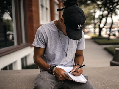 A focused man journaling outdoors, capturing moments of personal growth.