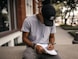 person in black adidas cap sitting on bench writing on notebook