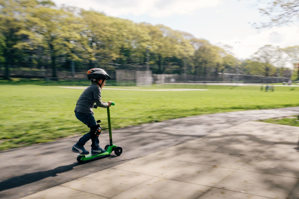 boy riding green kick scooter