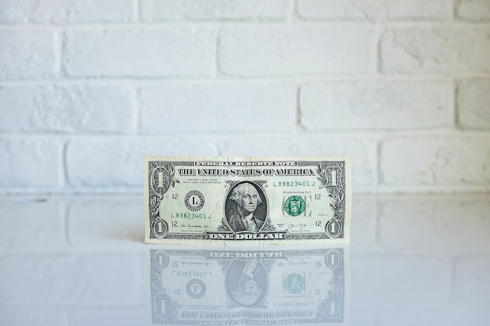 Billete de 1 dólar estadounidense sobre superficie blanca