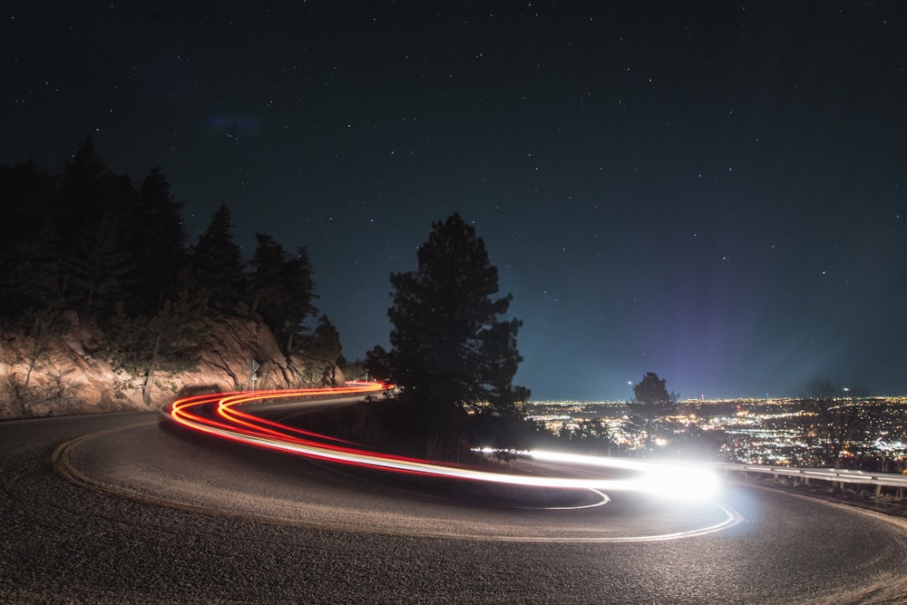 Fotografía de lapso de tiempo en carretera curva al lado de un árbol