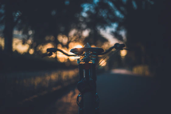 A close-up of a biker's gloved hand gripping the handlebar with a sunset in the background.