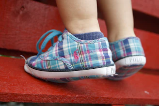 Close-up of a toddler’s feet in stylish boots, stepping on a vibrant playground surface.