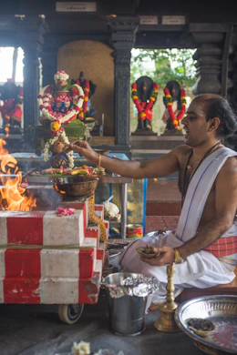 A priest performing a traditional puja with sacred fire and offerings in a peaceful setting