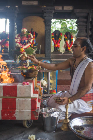An experienced priest performing a traditional puja with flowers and holy fire.