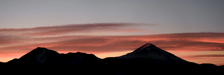 Silhouetted mountain ridgeline against a pink and orange sunset sky, evoking the Colorado Front Range