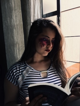 Anahita Diamond thoughtfully reading a historical manuscript in a sunlit study.