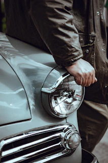 Model wearing a torque pulse muscle car jacket standing beside a classic Dodge Charger.