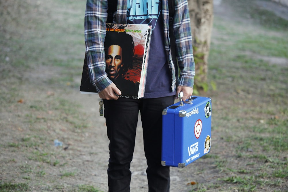 person in blue shirt holding blue suitcase