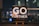 An inspirational message displayed on a small easel features bold white text that reads 'GO FURTHER.' against a cosmic background full of stars and galaxies. The scene is set indoors with a blurred night cityscape in the background, offering colorful bokeh effect lights.