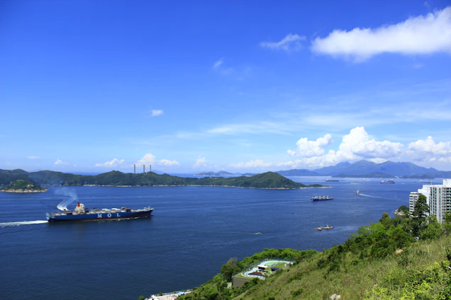 A vibrant cargo ship navigating turquoise waters between lush Indonesian islands under a bright sky.