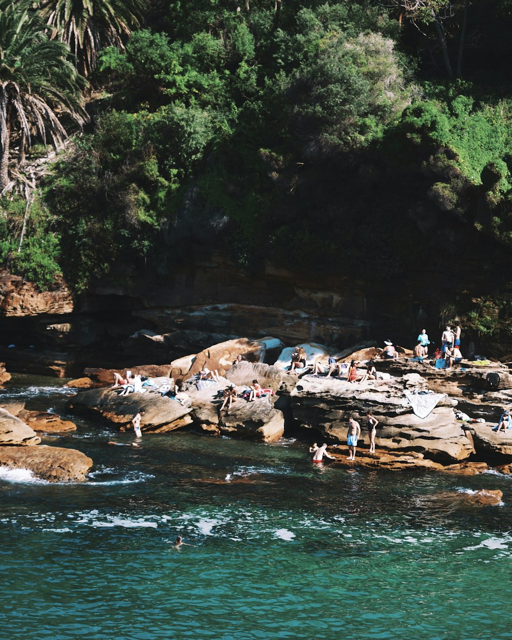 people on rock and body of water