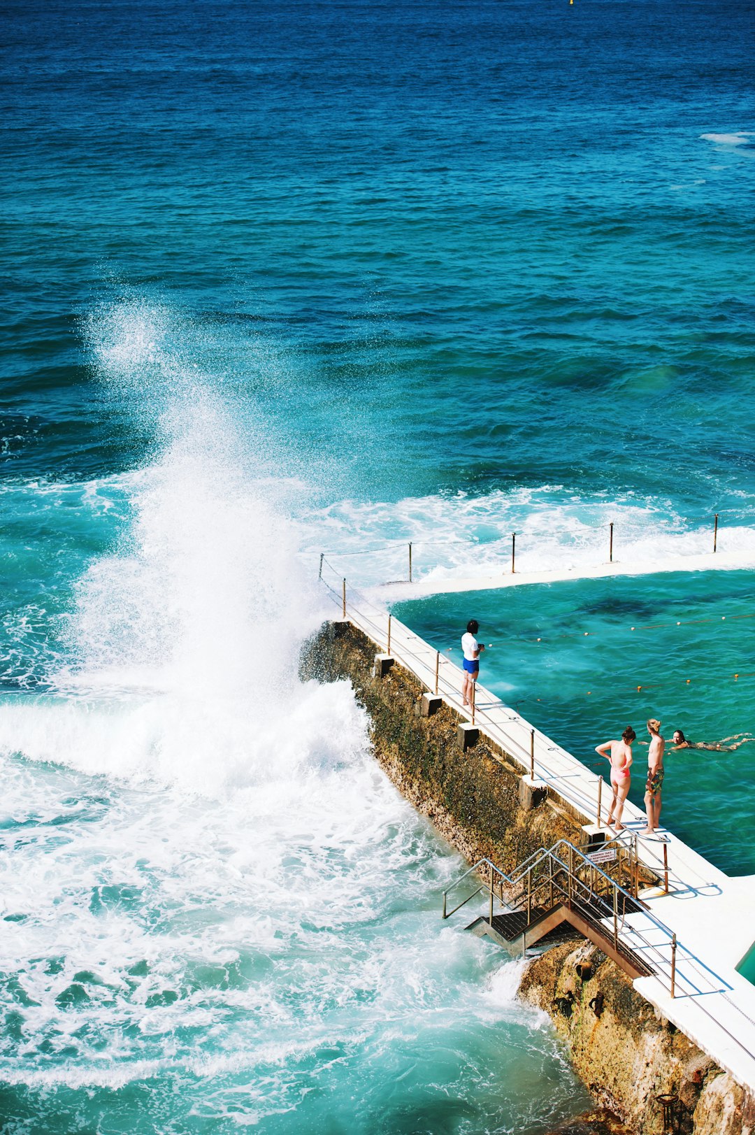 people standing beside pool next to the sea