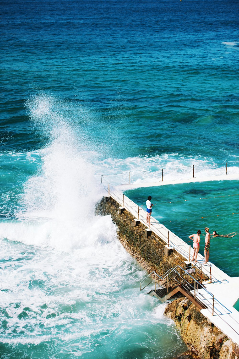 pessoas em pé ao lado da piscina ao lado do mar