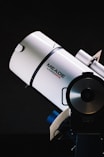 white Meade LX200GPS telescope beside black wall