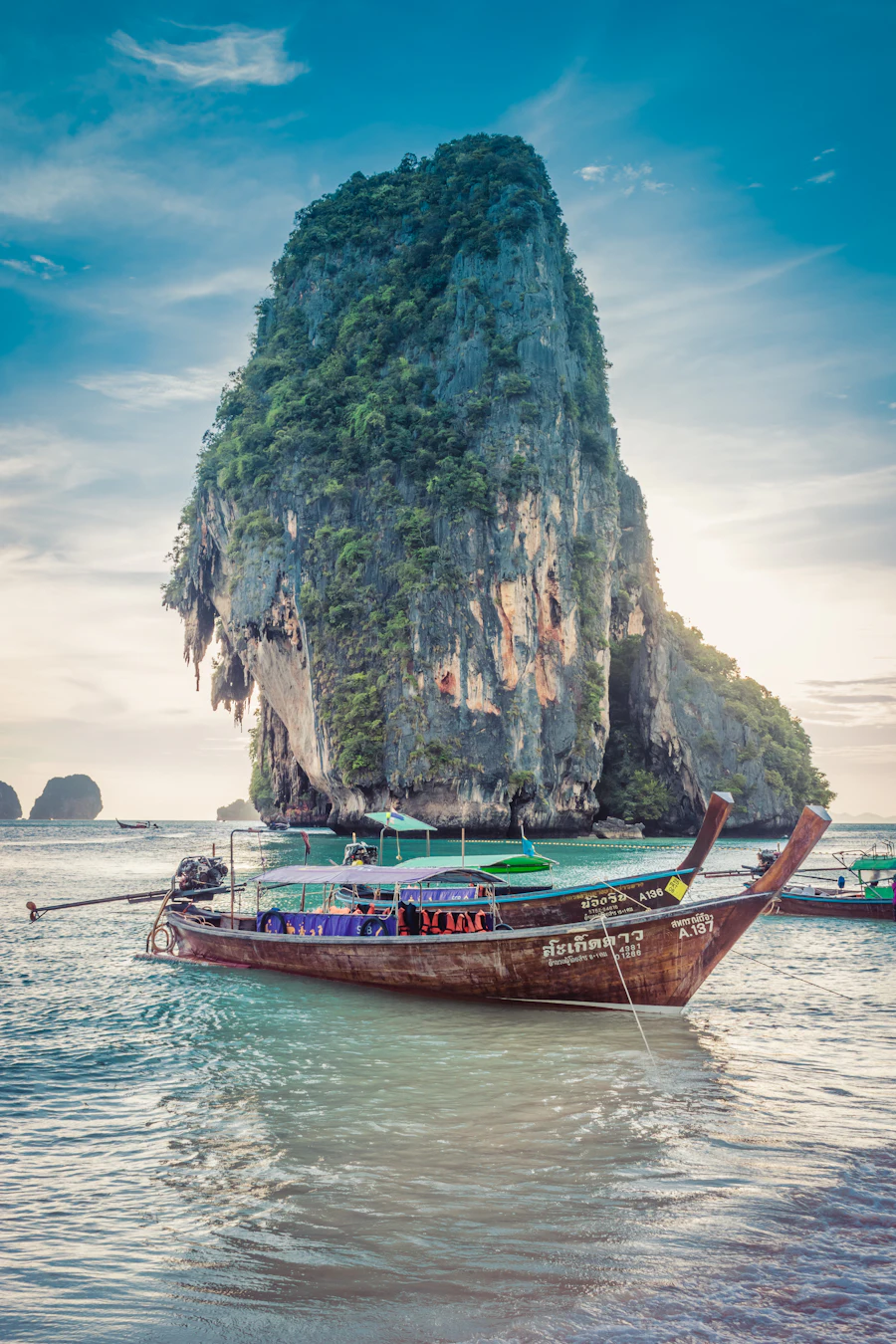 A longtail boat moored beneath the limestone headland at Railay beach