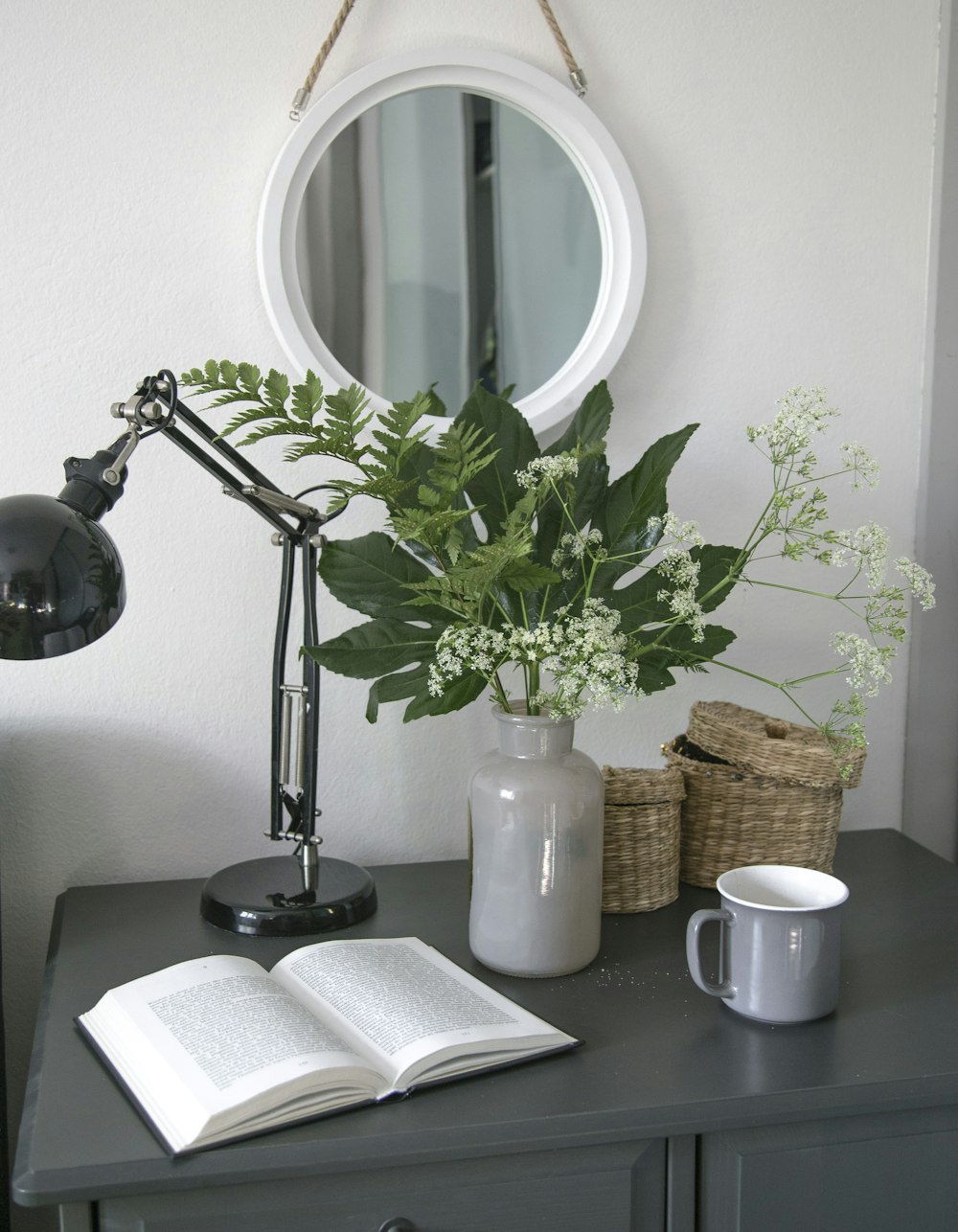 silver and black desk lamp beside white ceramic mug on black wooden table