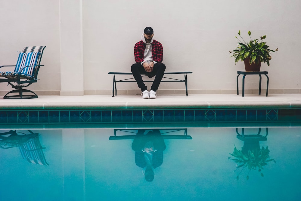 man sitting on black bench near pool