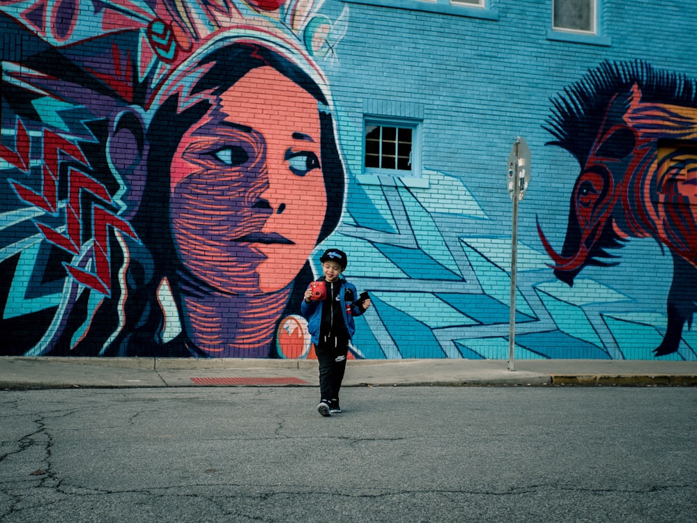 boy standing near vandalism art during daytime