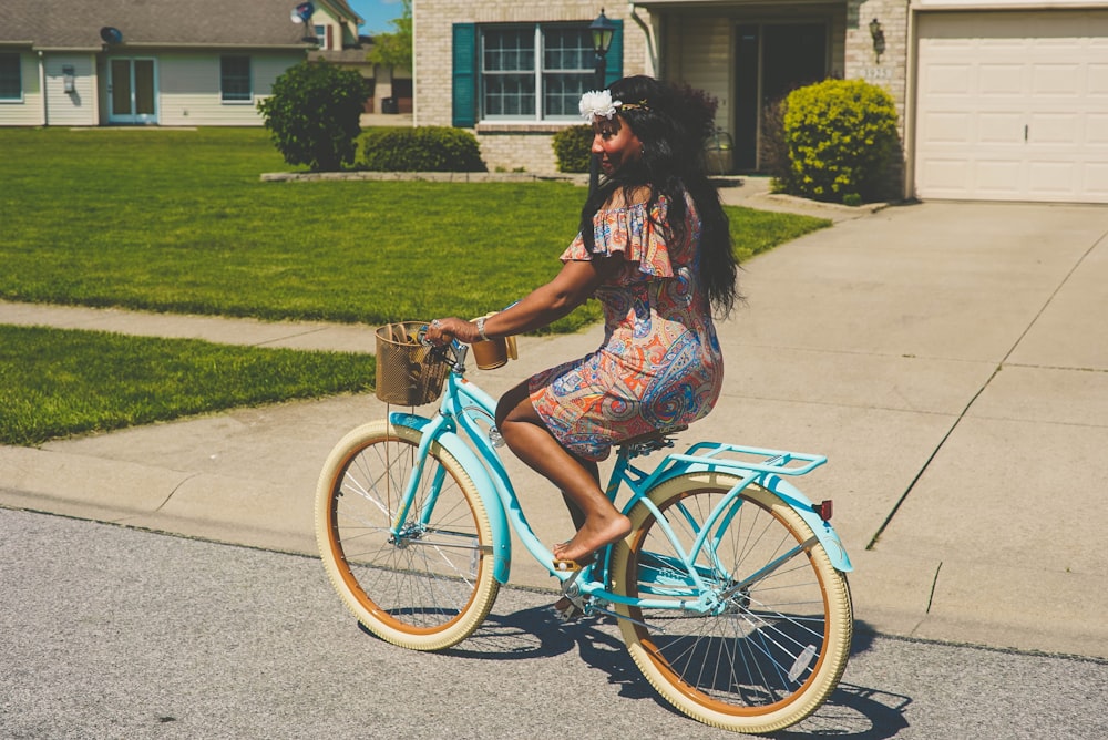 femme en robe marron et bleu chevauchant un vélo bleu