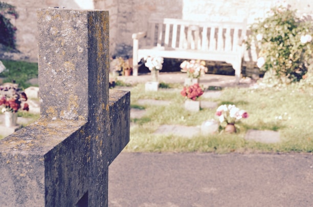 A caring professional gently cleaning a weathered headstone surrounded by fresh flowers.