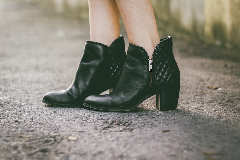 femme en bottes noires à talons épais debout sur un sol gris