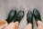 Two pairs of legs are visible, each wearing black leather shoes. One pair is wearing lace-up boots, while the other is wearing slip-on ankle boots. The ground is made of rough, textured concrete.