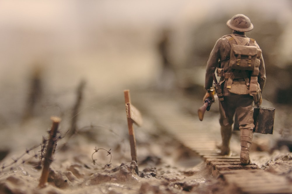 Soldat geht auf Holzweg, umgeben von Stacheldraht selektive Fokusfotografie