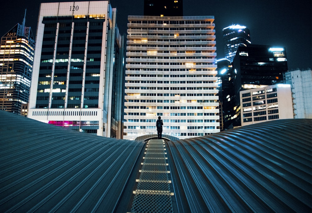 pessoa em pé no telhado do edifício com edifícios da cidade no fundo