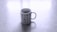 A white coffee mug printed with various black geometric and abstract symbols sitting on a light gray surface.