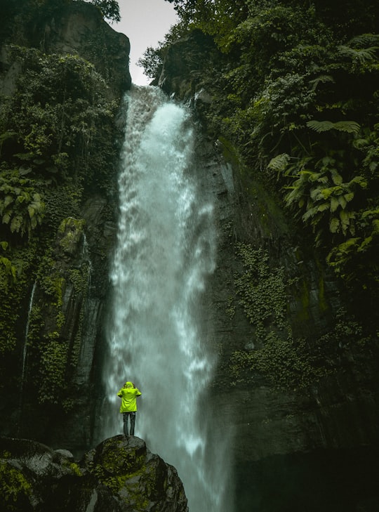 man standing on rock infront of waterfalls in Malang Indonesia