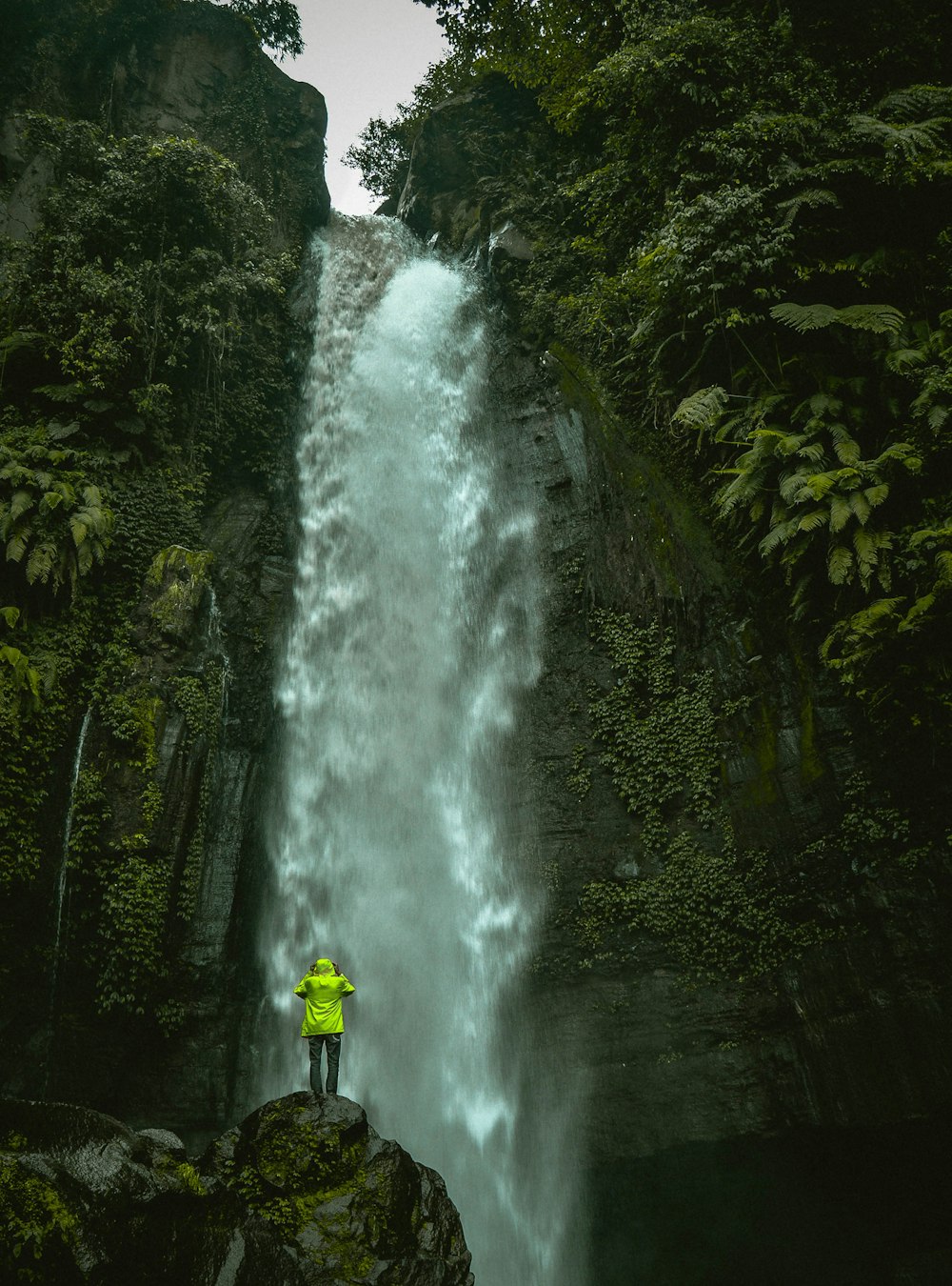Homem em pé na rocha em frente a cachoeiras